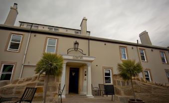 a beige building with a white trim , featuring a balcony and potted plants , under a cloudy sky at Beadnell Towers Hotel