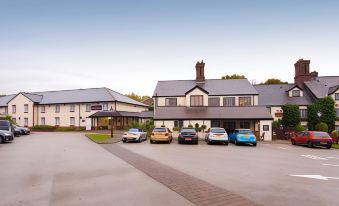 a parking lot with multiple cars parked in front of a building , including a blue car and a yellow car at Premier Inn Northwich (Sandiway)