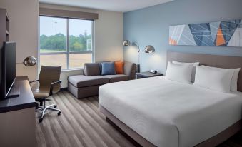 a modern hotel room with a large bed , couch , and desk , along with a view of the outside through a window at Hyatt House Charleston/Mount Pleasant