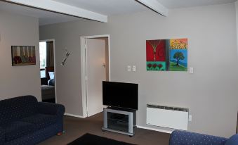 a living room with a tv mounted on the wall , blue couches , and a painting on the wall at Diplomat Motel