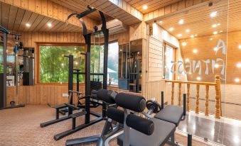 a gym with a variety of exercise equipment , including weights and a treadmill , in front of a wooden cabin at Hotel Mirage