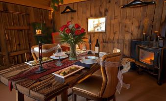 a dining room with a wooden table set for a meal , surrounded by chairs and candles at Zion Mountain Ranch