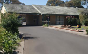 "a large house with a driveway and a sign that says "" used house "" on it" at Peppinella Motel