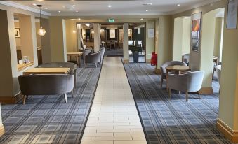 a long hallway with a white and blue checkered carpet leads to a room with chairs and a long table at Airport Inn Manchester