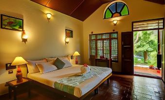 a spacious bedroom with a large bed and a bathroom attached to it , surrounded by windows at Somatheeram Ayurveda Village