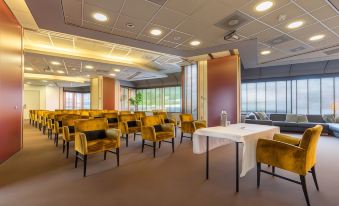 a conference room with yellow chairs and a white table , set up for a meeting at Leonardo Hotel Lelystad City Center