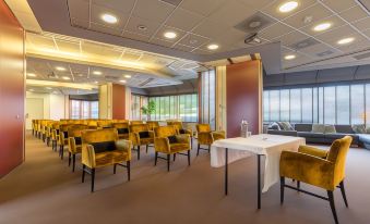 a large conference room with multiple chairs arranged in rows and a table in the center at Leonardo Hotel Lelystad City Center