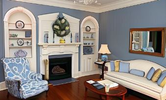 a cozy living room with blue and white furniture , including a couch , chairs , and a fireplace at Harmony Hill Bed & Breakfast