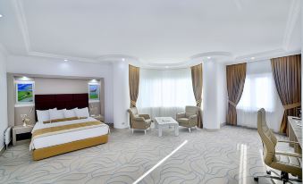 a spacious hotel room with a large bed , two chairs , and a couch , all set against white walls and a blue carpet at New Marathon Hotel