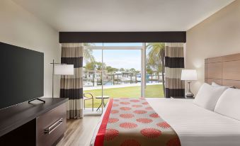 a bedroom with a large window overlooking a grassy field , creating a serene and inviting atmosphere at Ramada by Wyndham Sarasota Waterfront