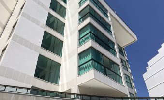 a modern white building with large windows and a green balcony is shown against a clear blue sky at Sophia II Residence Inn