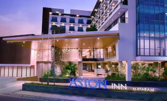 "a hotel named "" aston inn "" is lit up with blue lights at night , surrounded by trees and buildings" at ASTON Inn Mataram