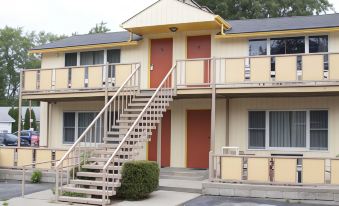 a two - story apartment building with a staircase leading up to the second floor , surrounded by grass and trees at Indiana Beach Accommodations