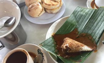 a table with plates of food , a cup of coffee , and a bowl of soup at De' Chukai Hotel