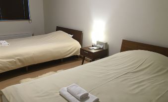 a room with two beds , one on the left and one on the right , both covered in white sheets at Ume