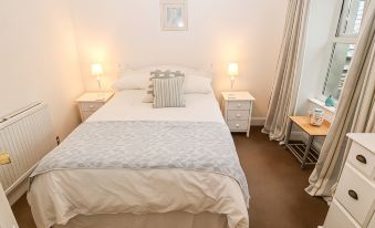 a neatly made bed with white linens and a blue blanket is shown in a bedroom at Avondale