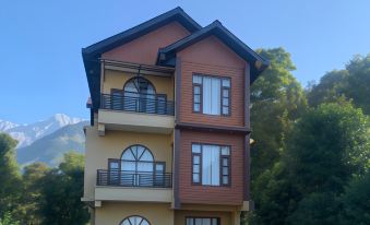 a two - story building with a brown and yellow exterior is surrounded by trees and mountains at The Sojourn