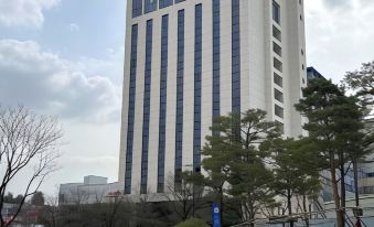 a tall building with blue and white stripes is surrounded by a park , trees , and grass at The Marevo