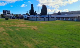 a grassy field with a building in the background and a blue sky overhead , creating a picturesque scene at Zig ZAG Motel & Apartments