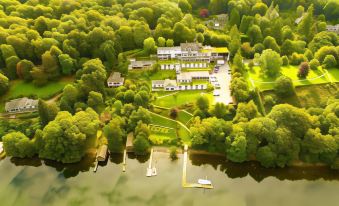 an aerial view of a large white building surrounded by trees and a body of water at Beech Hill Hotel & Spa