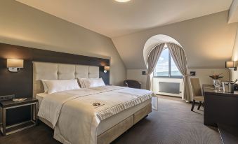 a large bed with white linens is in a room with a chair and a window at Hotel Victory