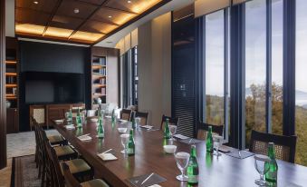 a long wooden table with green bottles and wine glasses is set up in a room with large windows at Plataran Bromo