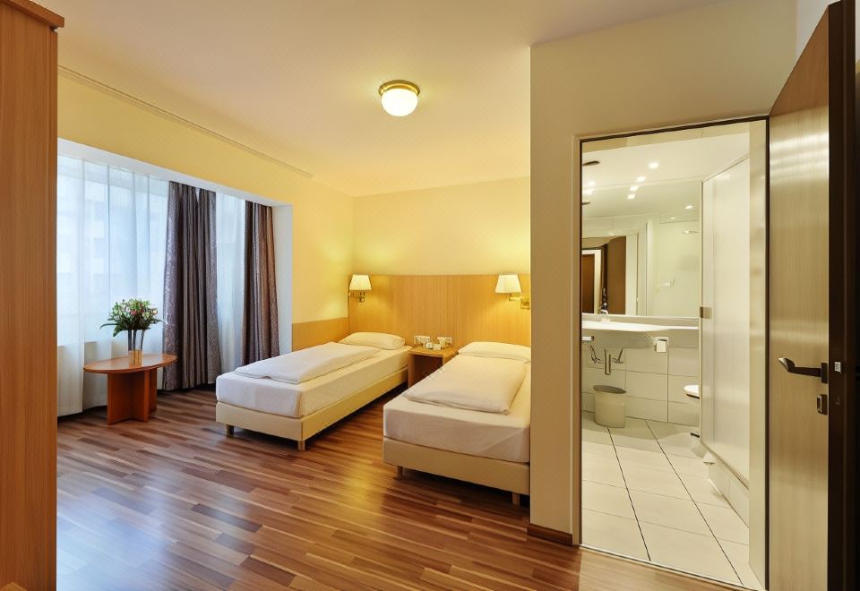 a hotel room with two beds , one on the left and one on the right side of the room at Bellevue Hotel