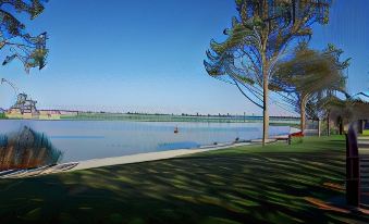 a serene landscape of a lake surrounded by trees and grass , with a clear blue sky above at Motel Riverbend