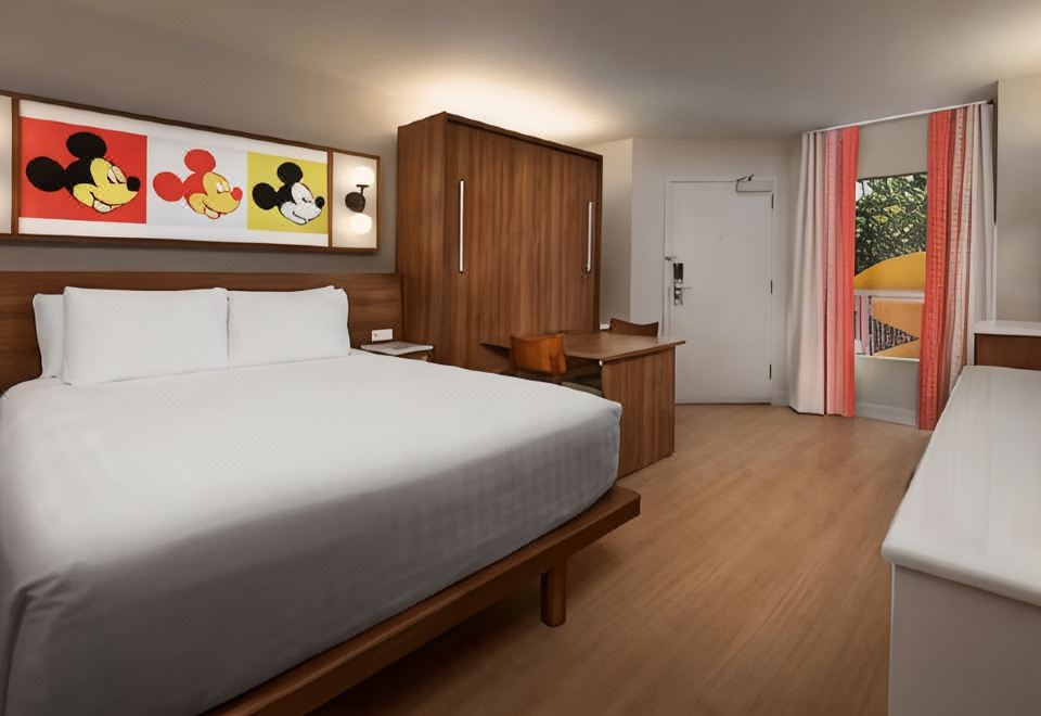 a hotel room with a king - sized bed , a desk , and a tv . also a chair in the room at Disney's Pop Century Resort - Classic Years