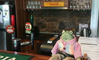 a living room with a man in a striped shirt sitting at a bar , surrounded by bottles of alcohol and other items at Little River Bed and Breakfast