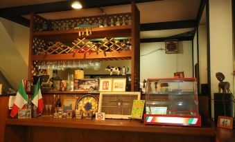 a bar with various items on display , including wine bottles and signs , under a wooden shelf filled with glasses at Flower Garden