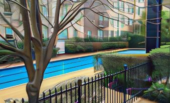 a view of a pool area through a fence , with an apartment building in the background at The Snug