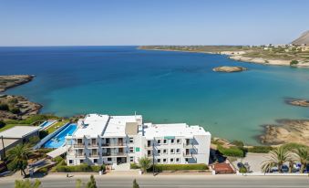 an aerial view of a large white building near the ocean , with a swimming pool visible in the background at Lena Beach Hotel