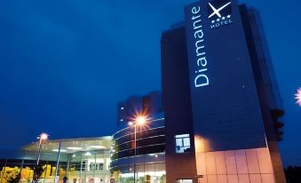 "a large hotel building with the word "" diamant "" on its side , located in a city at night" at Hotel Diamante