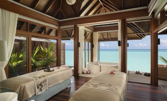 a luxurious beach - side resort with two beds , a bathtub , and a view of the ocean at Anantara Dhigu Maldives Resort - Special Offer on Transfer Rates for Summer 2024