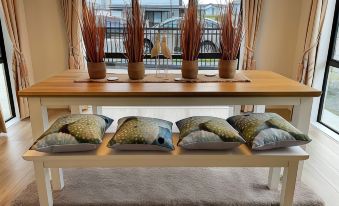 a wooden table with four pillows and a window in the background , creating a cozy atmosphere at Flat Bush Holiday Accomodation