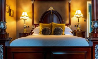 a bed with a white comforter and gold and yellow pillows is shown in a dimly lit bedroom at Melville Castle Hotel