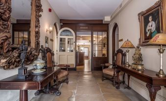 a foyer with a wooden table , chairs , and an entrance to the building through an open door at The Haycock Manor Hotel