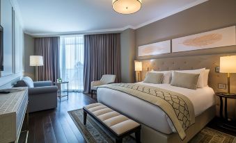 a large bed with white linens is in a hotel room with wooden floors and modern furniture at David Tower Hotel Netanya by Prima Hotels - 16 Plus