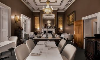 a dining room with a long table set for a formal dinner , surrounded by chairs and a fireplace at Quamby Estate