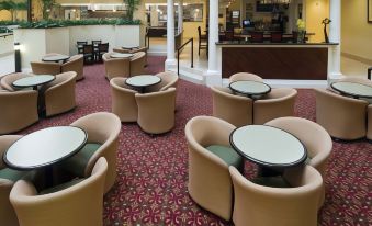 a large hotel lobby with various seating options , including couches and chairs , as well as a bar area at Embassy Suites by Hilton Fort Myers Estero