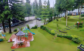 a playground with a swing , slide , and other play equipment surrounded by trees and grass at Alfa Resort Hotel and Conference