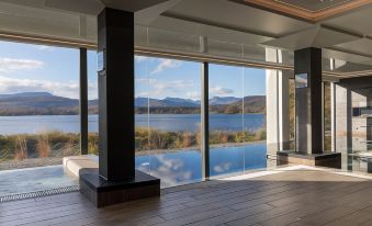 a modern , minimalist living room with large windows offering a view of a lake and mountains at Low Wood Bay