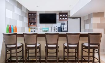 a bar area with multiple chairs and tables , as well as a television mounted on the wall at Ramada by Wyndham Minneapolis Golden Valley