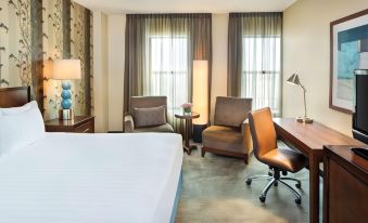 a hotel room with a bed , two chairs , a desk , and a lamp on the side of the bed at Hyatt Regency Buffalo Hotel and Conference Center