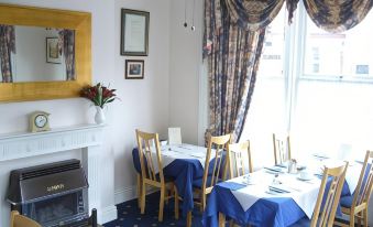 a dining room with blue tablecloths and chairs , a fireplace , and a mirror on the wall at Diamonds Villa Near York Hospital