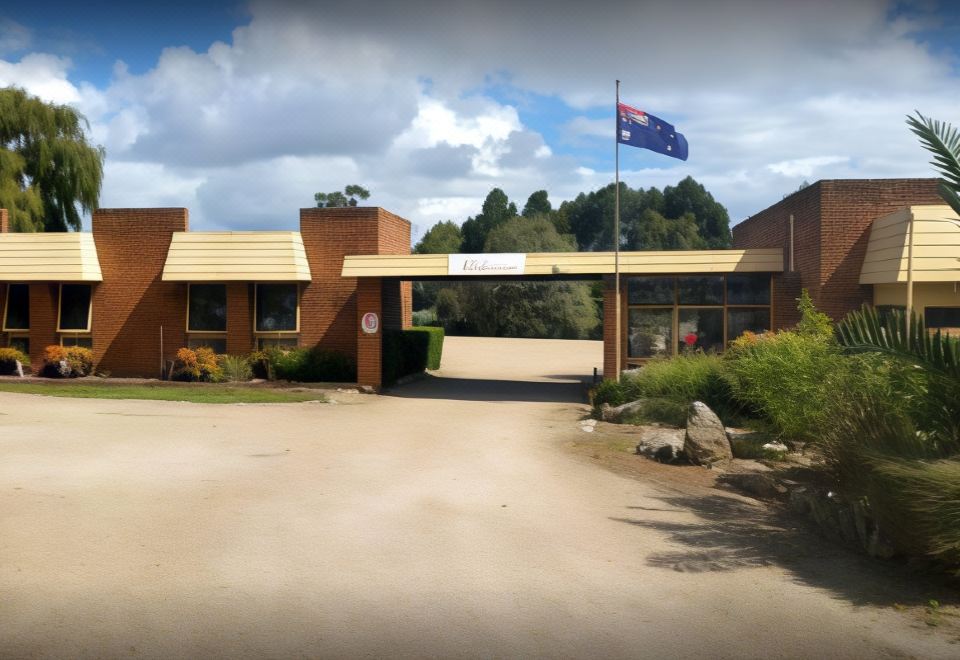 a brick building with a sign on the front , and an australian flag flying outside at Toora Lodge Motel