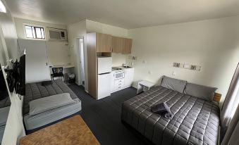 a modern bedroom with a bed , couch , and kitchenette in a white color scheme at Hi-Way Motel Grafton - Contactless