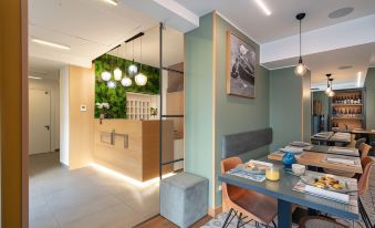 a modern dining area with a wooden table , chairs , and a green wall mural at Avenue Boutique Hotel