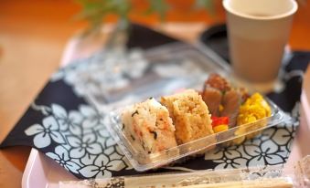 a clear plastic container filled with various types of sushi , placed on a dining table at Toyoko Inn Meitetsu Chiryu Ekimae